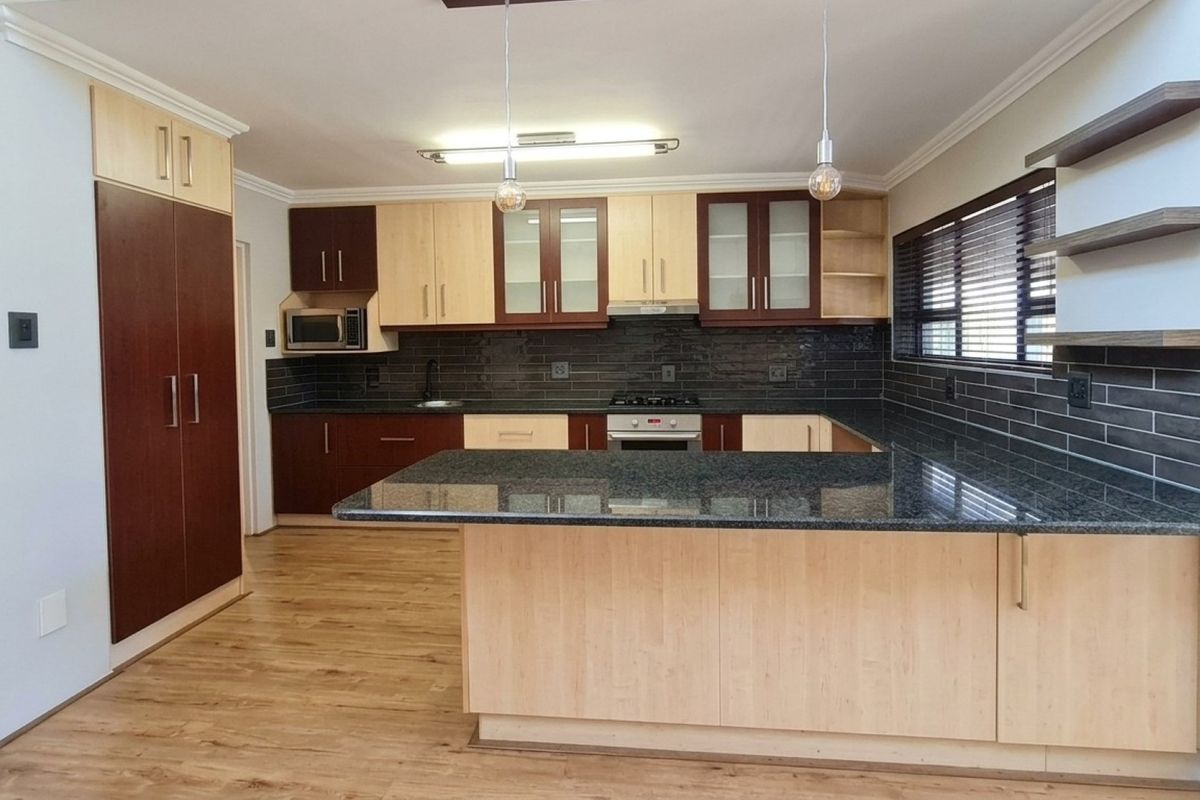 Modern kitchen featuring two-tone cabinetry, granite countertops, a gas hob, built-in oven, and stylish subway tile backsplash with ample storage space.