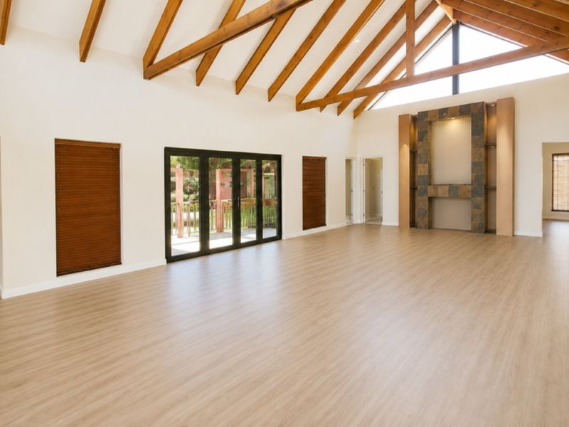 Spacious living area featuring a high vaulted ceiling with exposed timber rafters, a tiled feature fireplace, and bi-fold doors opening to the outdoors.