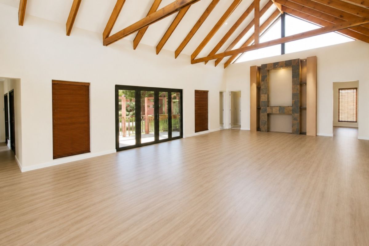 Spacious living area featuring a high vaulted ceiling with exposed timber rafters, a tiled feature fireplace, and bi-fold doors opening to the outdoors.