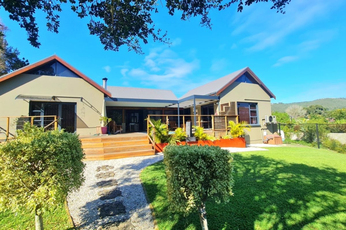 Rear view of the house featuring a spacious timber deck, landscaped garden, and stone pathway leading to the main entrance.