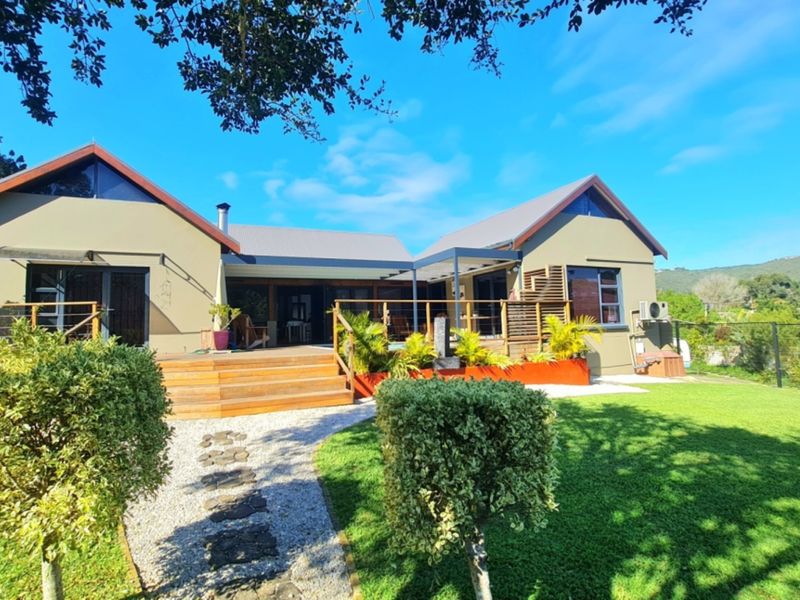 Rear view of the house featuring a spacious timber deck, landscaped garden, and stone pathway leading to the main entrance.