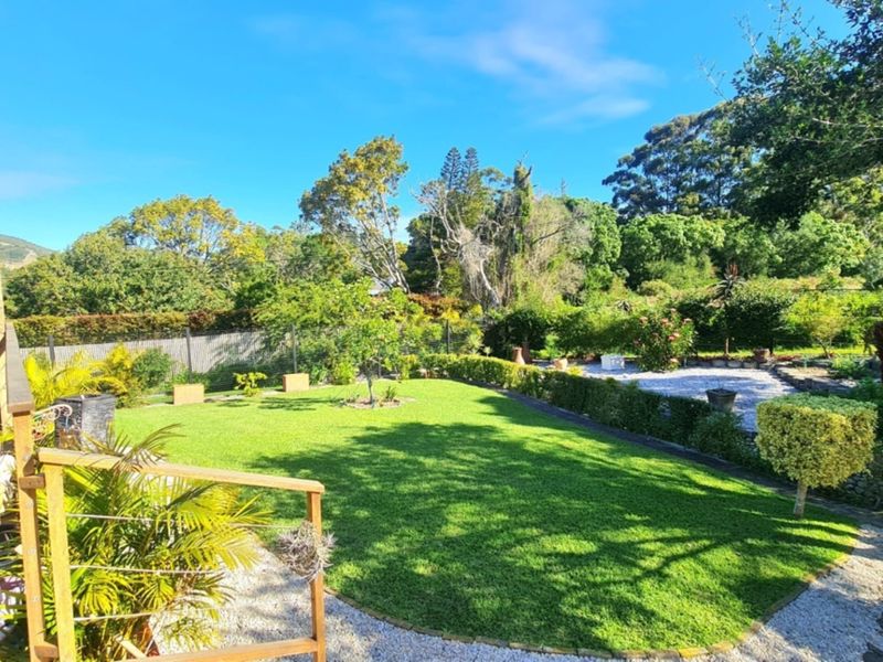 A well-maintained garden featuring a lush lawn, timber decking, gravel pathways, and established perimeter hedging, providing a private outdoor space.