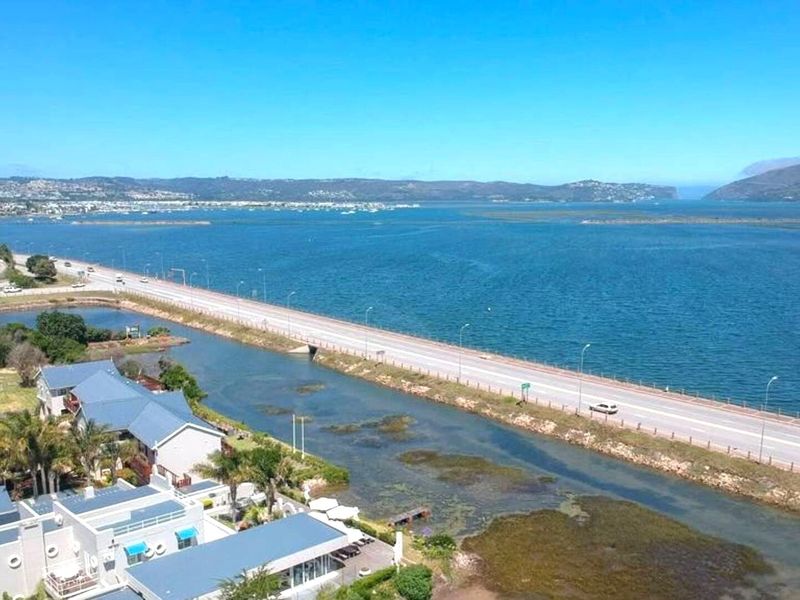 Aerial view of a coastal residential property situated along a scenic estuary and main road.