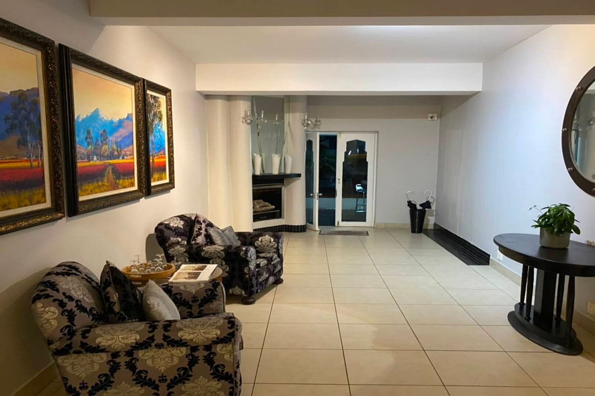 Spacious living area featuring neutral tiled flooring and a built-in fireplace, providing a functional and open layout with direct access to the exterior.