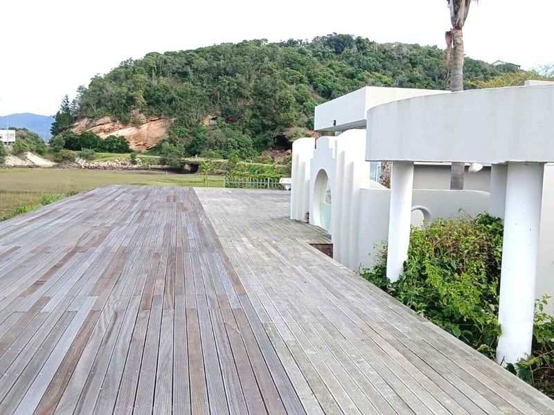 Spacious outdoor timber deck featuring architectural arched columns and views of the surrounding landscape.
