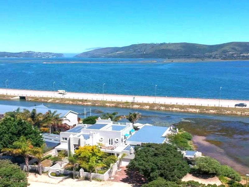Aerial view of the property showcasing its waterfront location, landscaped grounds, and proximity to the lagoon and main road.