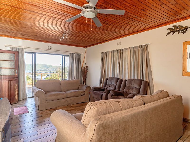 Spacious living room featuring a warm timber-clad ceiling, ceiling fan, and large sliding glass doors that open to a scenic outdoor view.