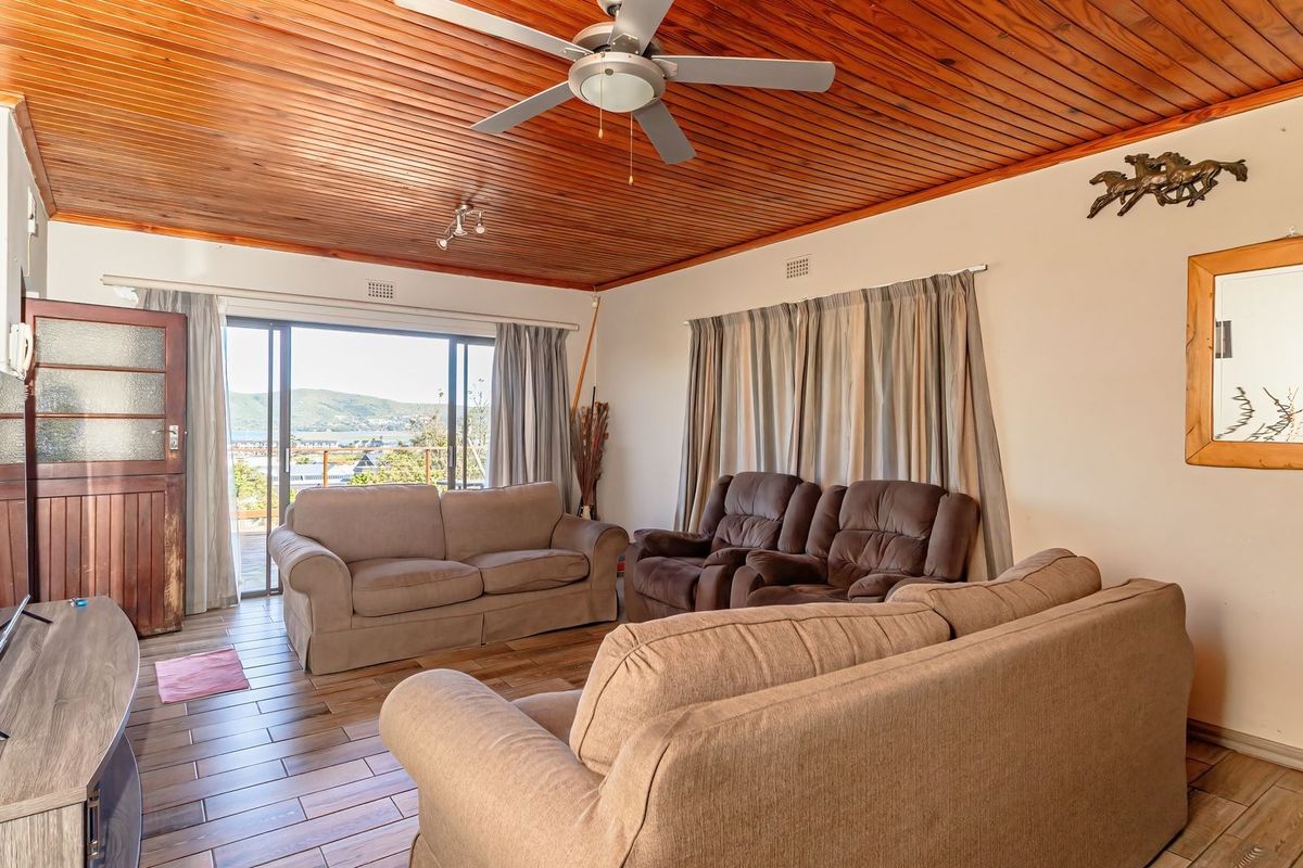 Spacious living room featuring a warm timber-clad ceiling, ceiling fan, and large sliding glass doors that open to a scenic outdoor view.