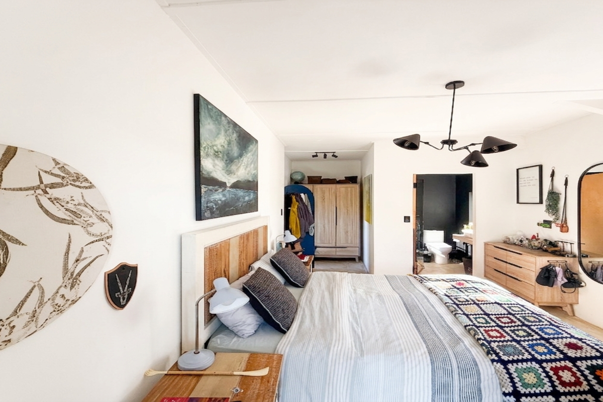 A well-lit bedroom featuring a modern multi-arm ceiling light and direct access to an en-suite bathroom.