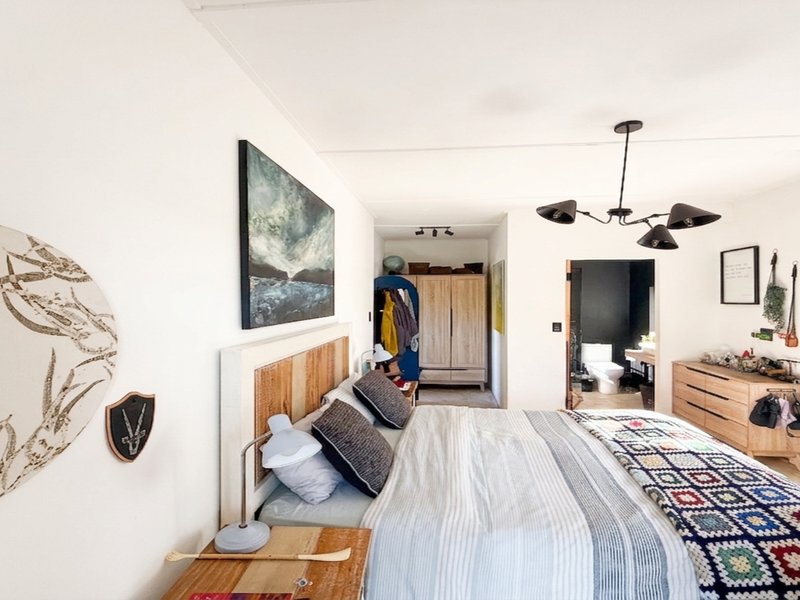 A well-lit bedroom featuring a modern multi-arm ceiling light and direct access to an en-suite bathroom.