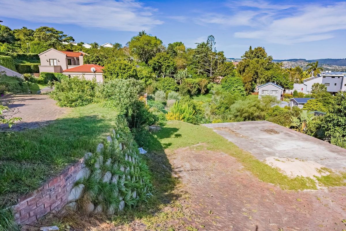 A sloped residential plot featuring a concrete slab foundation, established retaining walls, and mature garden surroundings in a quiet neighborhood setting.