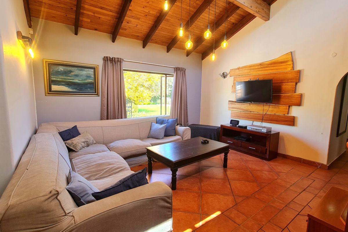 Cozy living room featuring exposed timber ceiling beams, warm terracotta floor tiles, and a decorative timber wall panel.