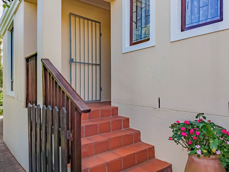 Exterior entrance featuring a tiled staircase with timber balustrade and a security gate, leading to the main dwelling access.
