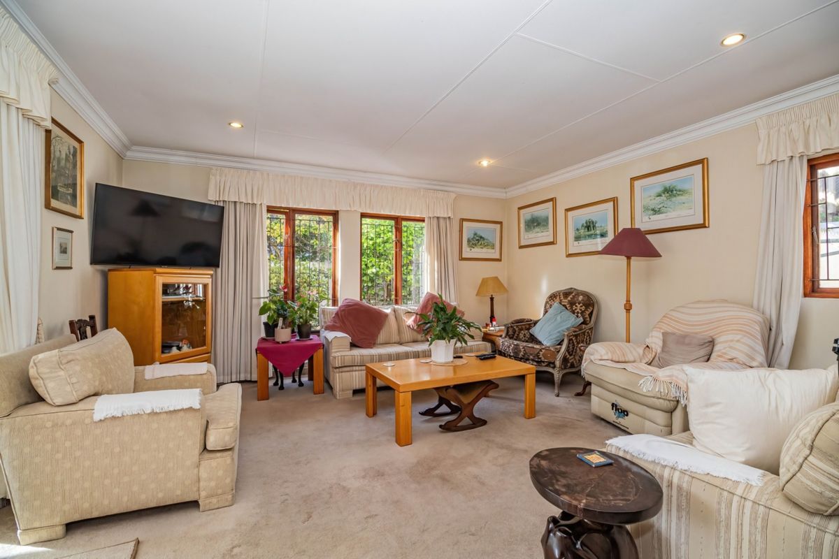 A comfortable living room featuring crown molding, recessed downlights, and timber-framed windows with security bars, offering a warm and traditional atmosphere.