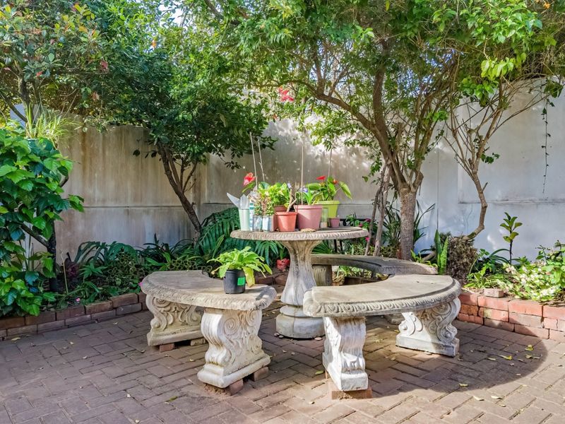 A private garden area featuring brick paving, mature trees, and a boundary wall, providing a quiet outdoor space.