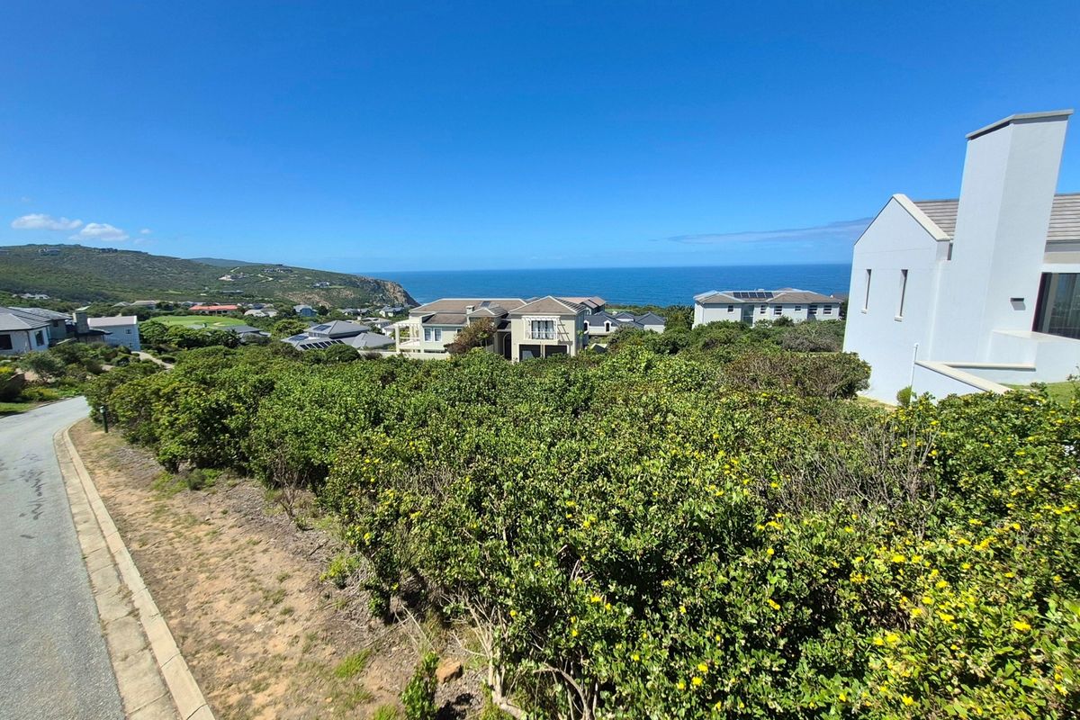 A scenic elevated view overlooking a residential estate with coastal landscape and ocean horizon in the background.