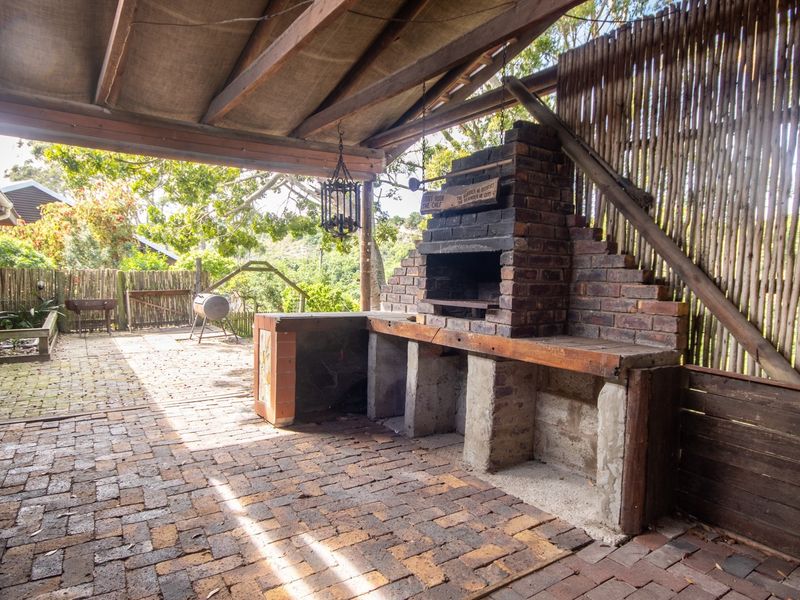 Covered outdoor patio area featuring a rustic brick built-in braai, brick paving, and timber roof structure, ideal for outdoor entertaining.