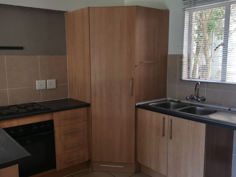 Functional kitchen featuring laminate cabinetry, built-in oven, electric hob, and a double bowl sink with tiled splashback.