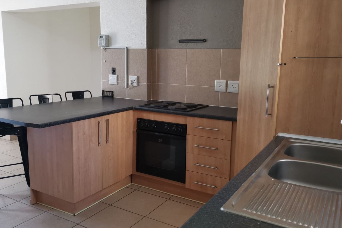 Functional kitchen featuring laminate cabinetry, built-in oven, electric hob, double bowl stainless steel sink, and a convenient breakfast bar area.