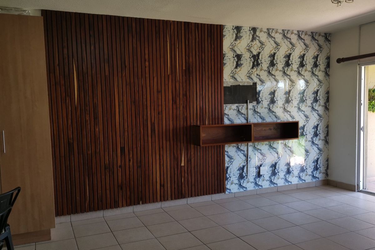 Living area featuring a combination of slatted wood and marble-effect wall finishes, ceramic floor tiles, and access to an outdoor patio.