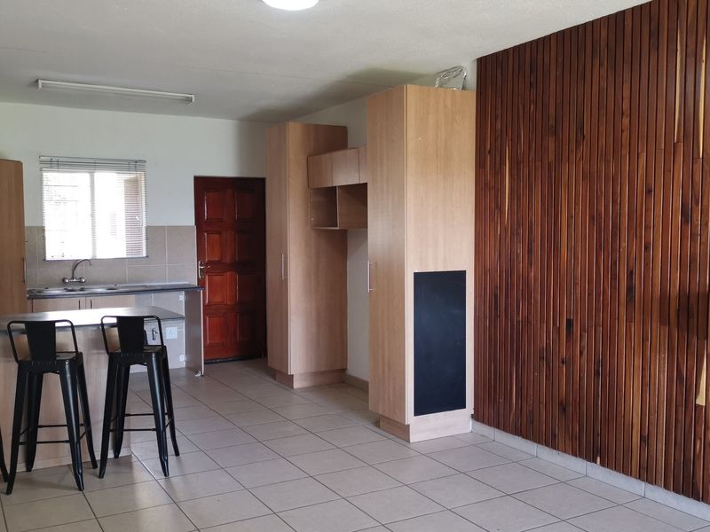 Open-plan living and kitchen area featuring tiled flooring, timber slat wall paneling, and built-in cabinetry with a breakfast counter.