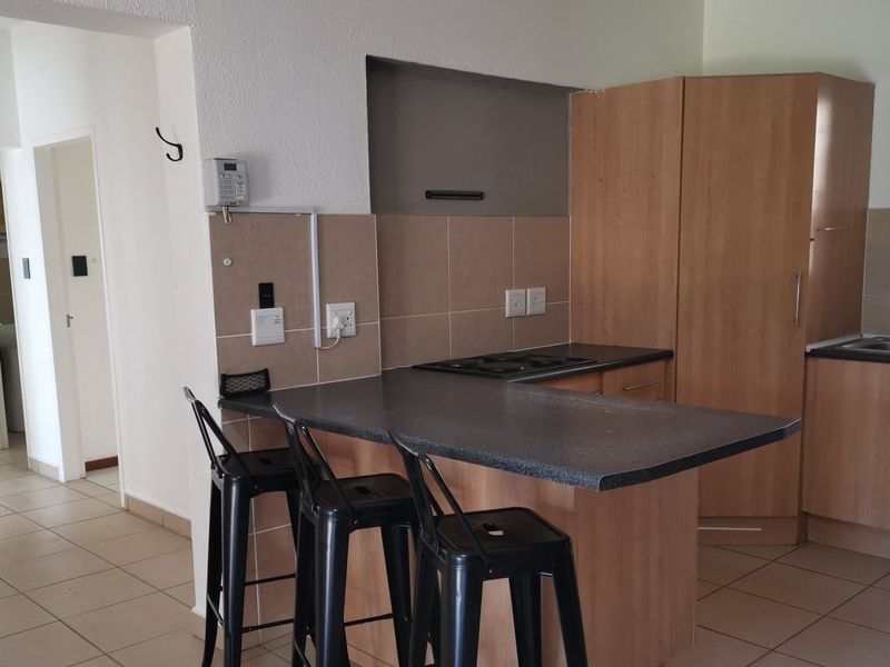 Functional kitchen featuring laminate cabinetry, a breakfast bar, built-in hob, and tiled backsplash, offering a practical layout for daily meal preparation.