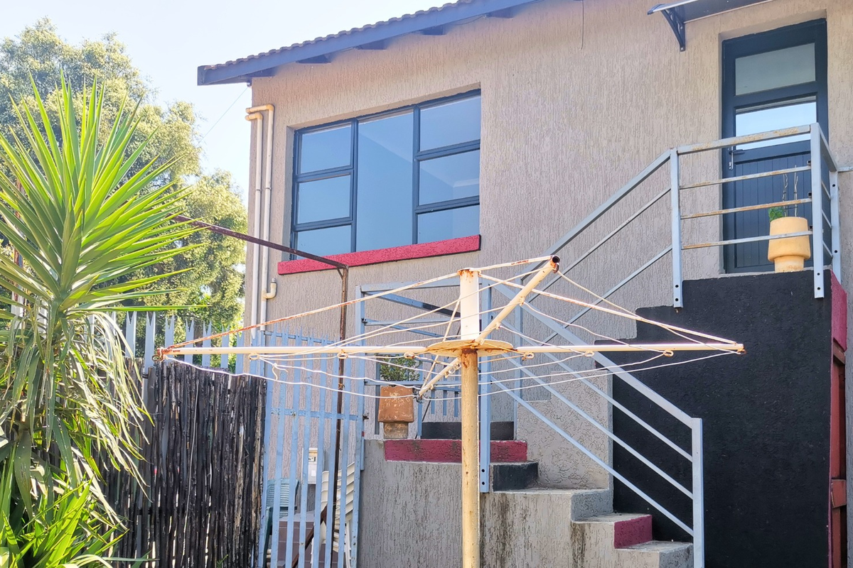 Rear exterior view of the apartment building featuring an external staircase with metal balustrades and aluminium window frames.
