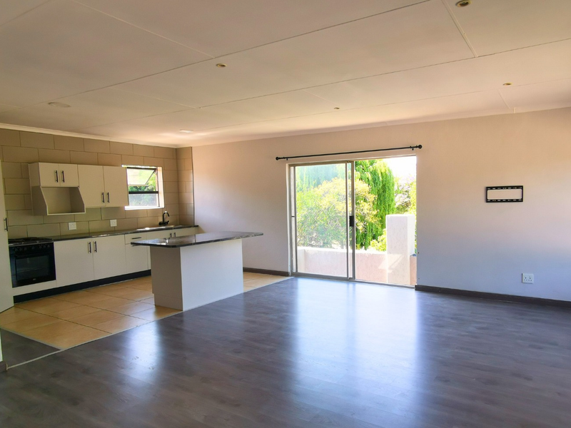 Spacious open-plan living area featuring a modern kitchen with granite countertops, built-in appliances, and direct access to an outdoor balcony through sliding glass doors.