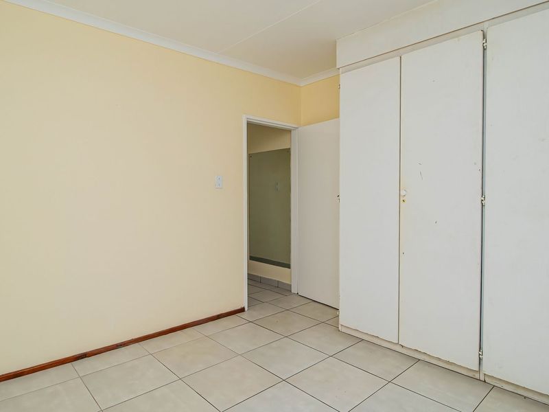An empty bedroom featuring tiled flooring and built-in cupboards, offering a neutral canvas for personalization.