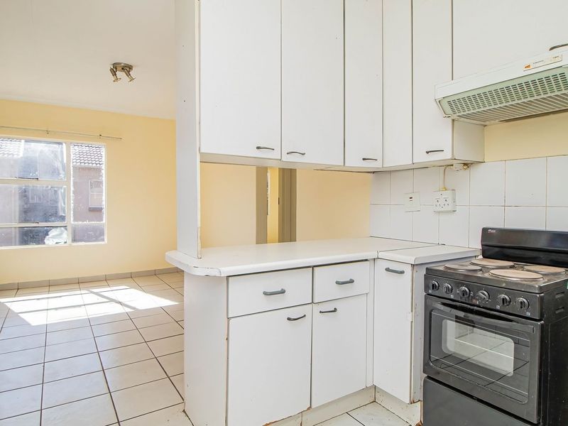Open plan kitchen and living area featuring tiled flooring and dated white cabinetry, offering a blank canvas for renovation and modernization.