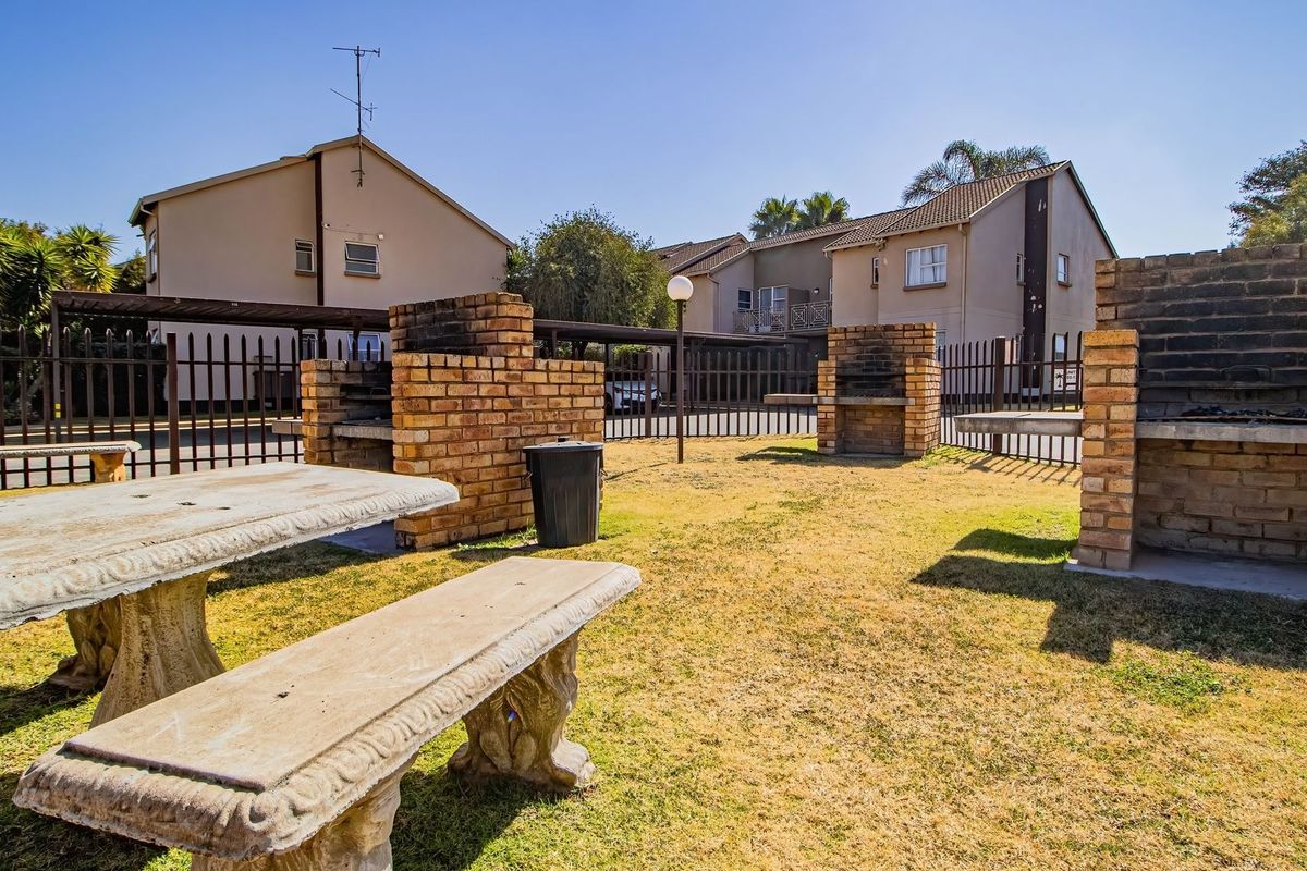 Communal outdoor area featuring multiple brick braai stands, concrete seating, and perimeter fencing within a residential flat complex.