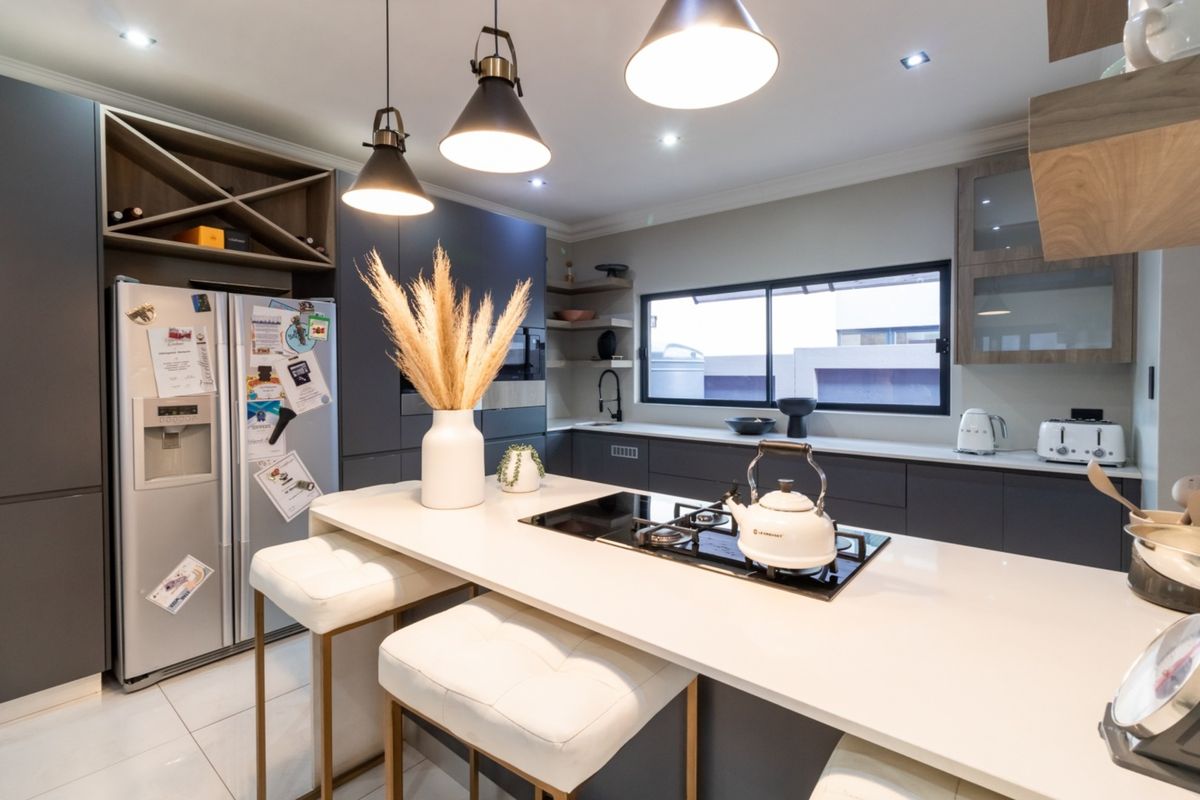 Modern kitchen featuring a central island with integrated gas hob, sleek cabinetry, stone countertops, and contemporary pendant lighting.