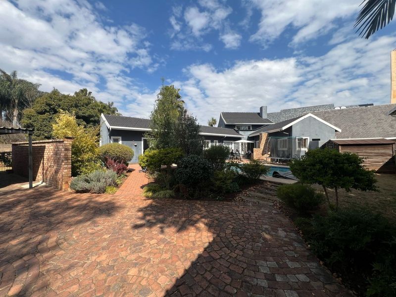 Spacious rear garden featuring a swimming pool, established landscaping, brick paving, and a functional outdoor storage shed, providing a private and well-maintained outdoor living area.