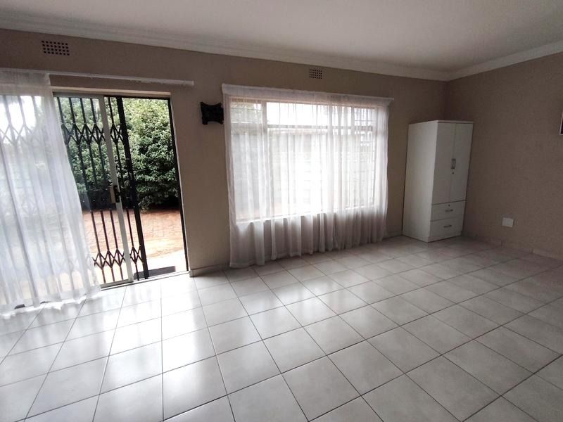 Spacious living area featuring neutral tiled flooring, large windows for natural light, and direct access to the outdoor patio through a sliding glass door.