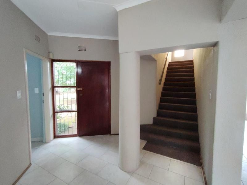 Entrance foyer featuring tiled flooring, a structural column, and a carpeted staircase leading to the upper level.