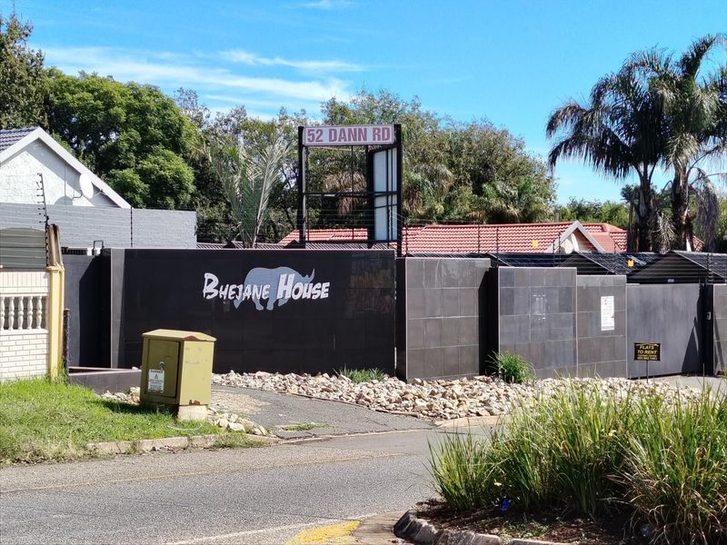 Front exterior view of the property featuring a tiled boundary wall, electric fencing, and clear street signage.
