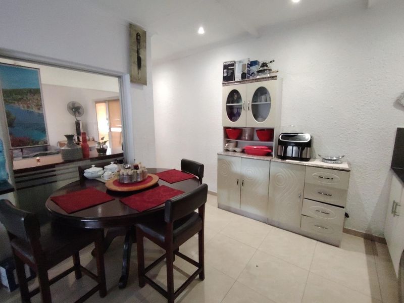 Dining area featuring tiled flooring, recessed downlighting, and built-in cabinetry, with an open-plan connection to the adjacent living space.