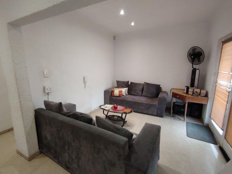A functional living room featuring tiled flooring, recessed downlighting, and textured wall finishes, providing a neutral base for interior updates.