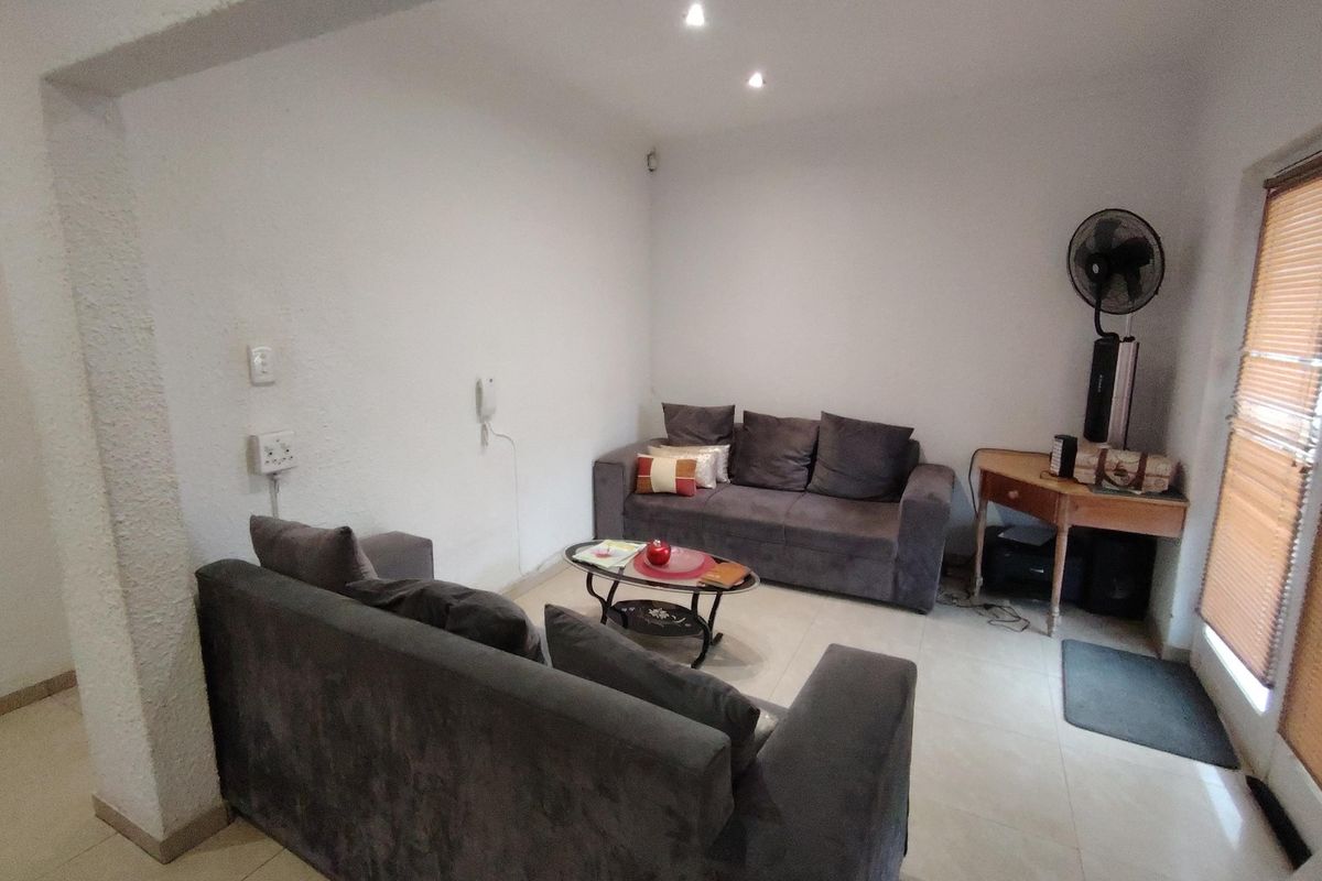 A functional living room featuring tiled flooring, recessed downlighting, and textured wall finishes, providing a neutral base for interior updates.