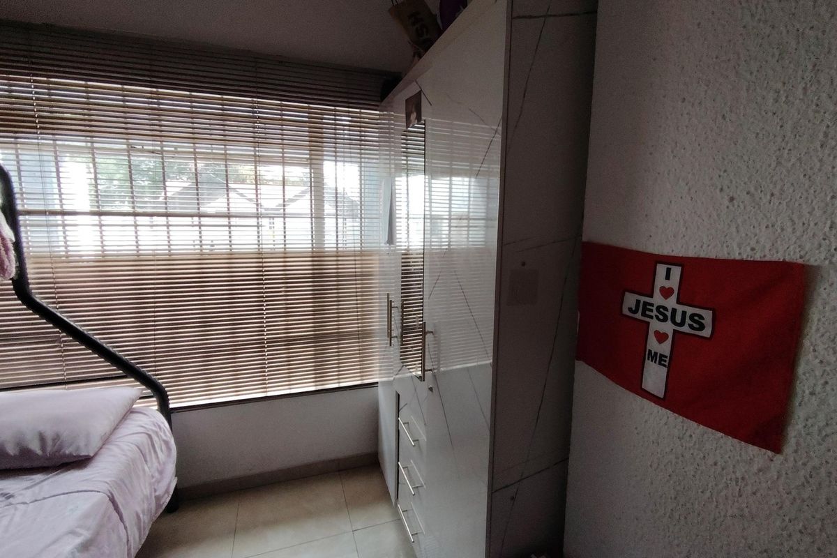 A bedroom featuring tiled flooring, a built-in wardrobe with a mirrored panel, and venetian blinds covering the window.