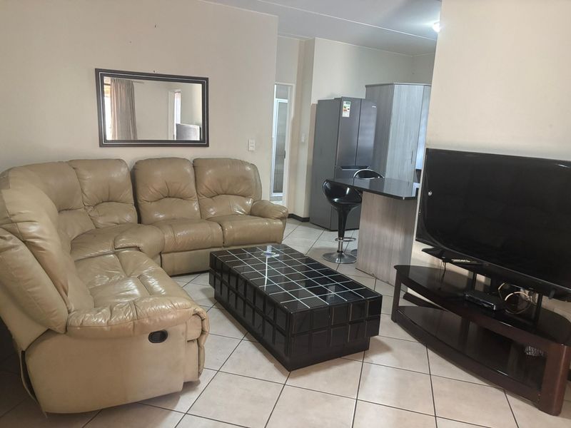 Open plan living area featuring ceramic floor tiles and a breakfast bar, seamlessly connecting the lounge and kitchen space.