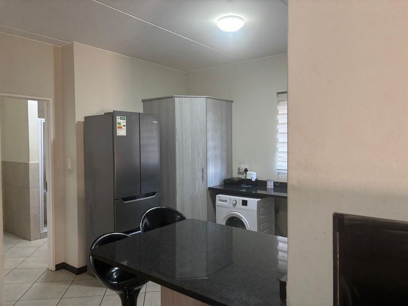 Compact kitchen area featuring granite countertops, built-in cabinetry, and tiled flooring, with a functional layout including space for laundry appliances.