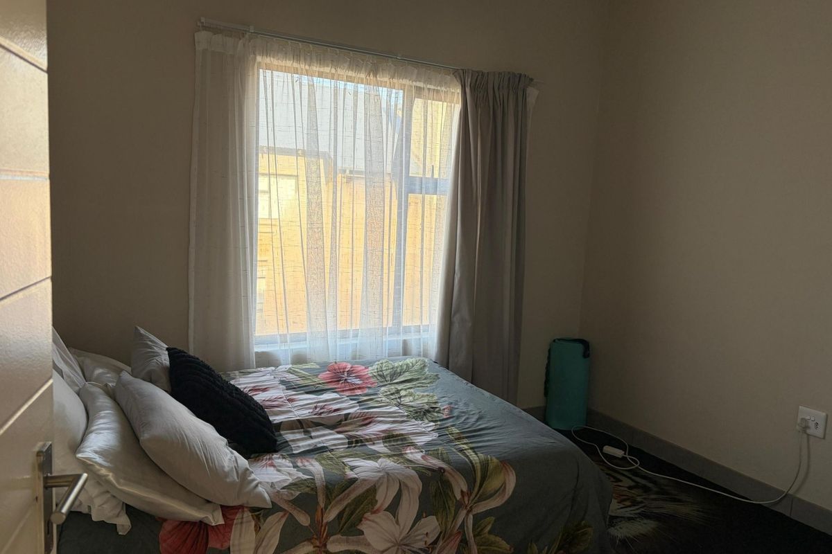 A standard bedroom featuring a window with curtains and neutral wall finishes, providing a functional space for rest.