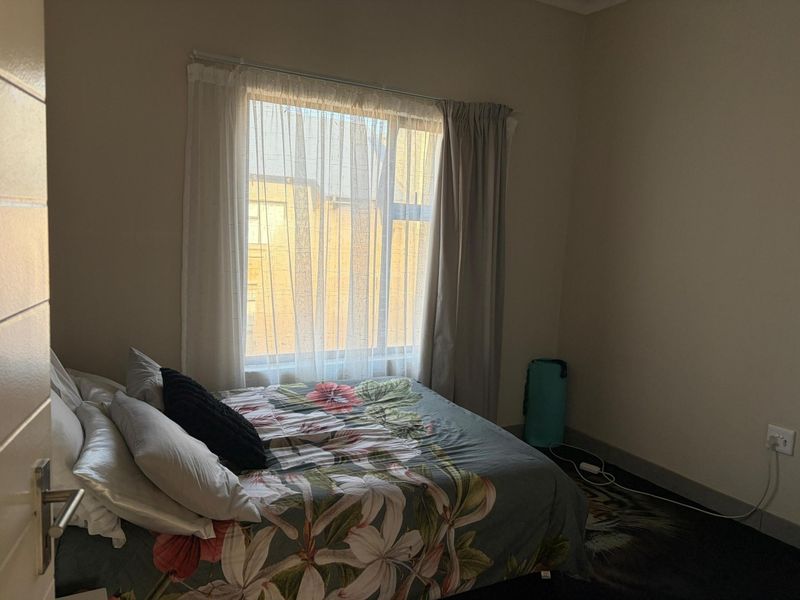 A standard bedroom featuring a window with curtains and neutral wall finishes, providing a functional space for rest.