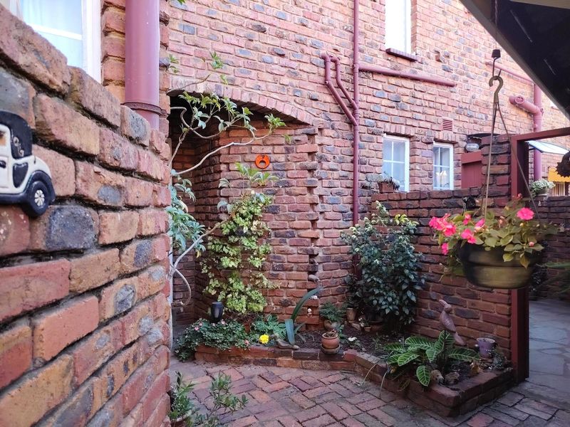 A charming, private rear courtyard featuring exposed brick walls, brick paving, and established garden beds with integrated planter boxes.