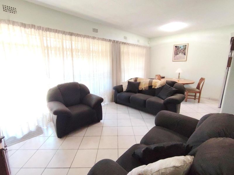 Spacious living area featuring neutral tiled flooring and large sliding glass doors that provide ample natural light.