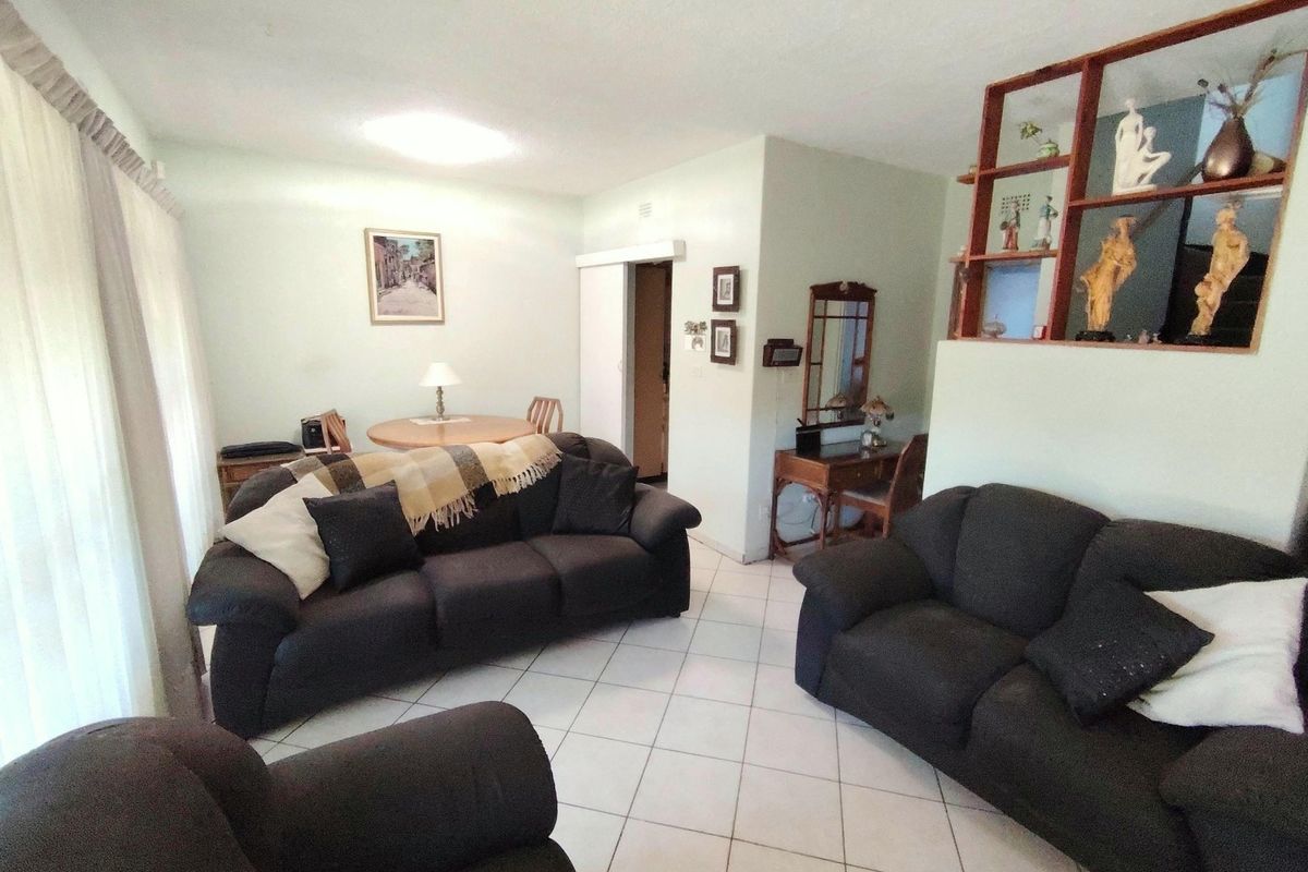 A spacious living room featuring tiled flooring and a built-in wooden display shelf, offering a functional layout for relaxation and dining.