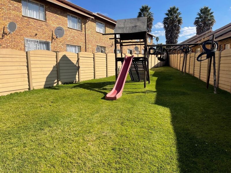 A private garden area featuring a lawn and a precast concrete boundary wall, situated alongside the apartment building.