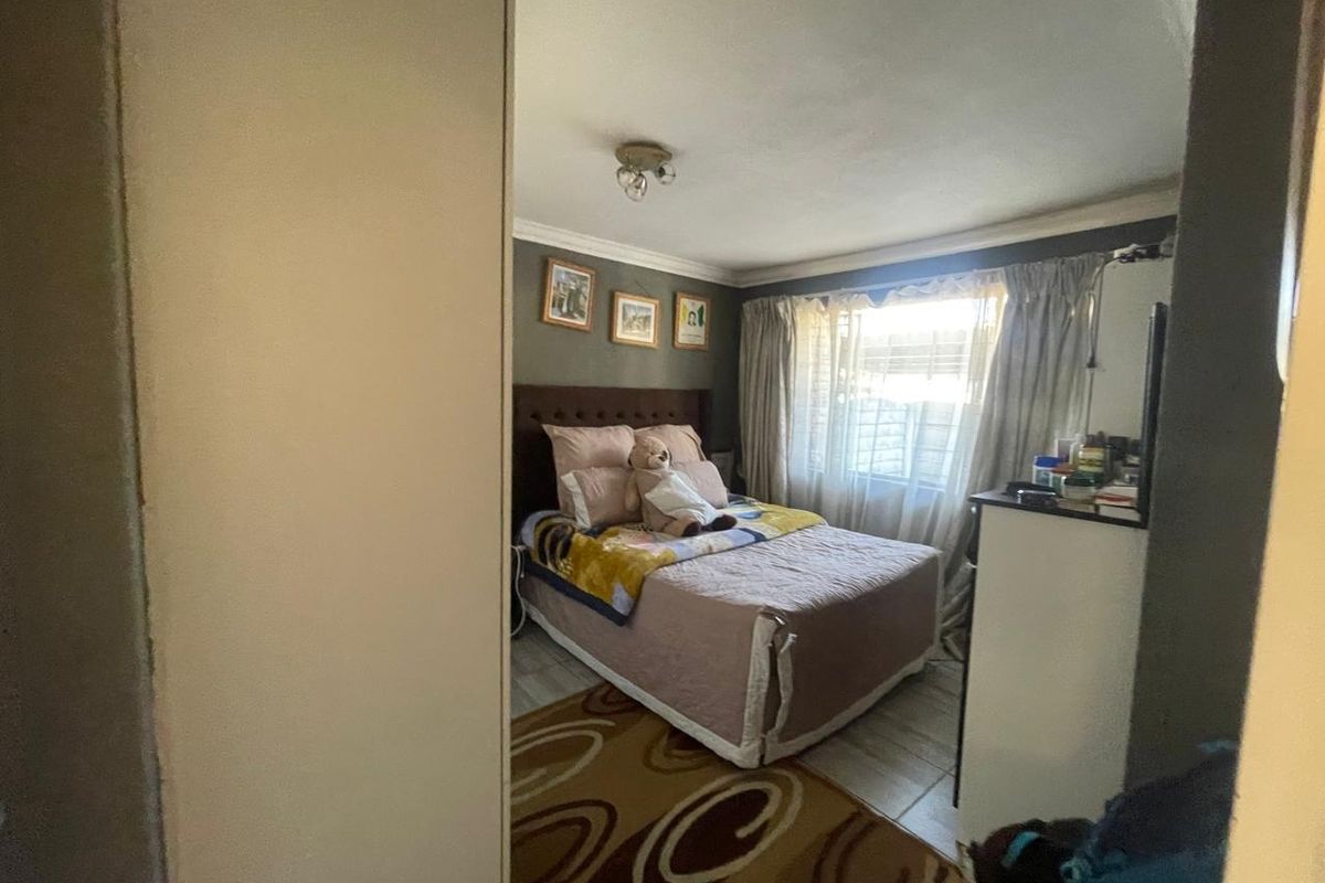 A standard bedroom featuring tiled flooring and natural light through window curtains.