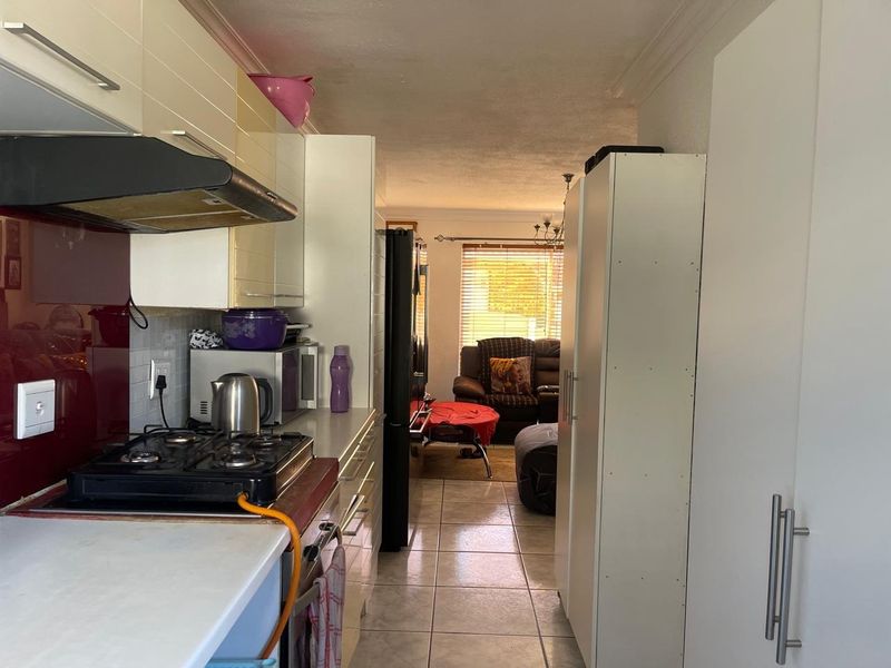 Open-plan kitchen and living area featuring tiled flooring, built-in cabinetry, and a gas hob with extractor fan.